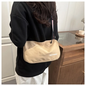 Dettaglio di una borsa a tracolla in tela beige con un cinturino a righe rosse e bianche