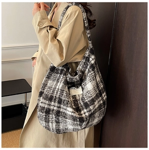 Close-up of black and white plaid wool shoulder bag with soft textured fabric and label