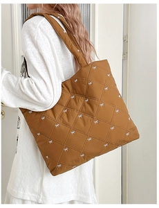 Close-up of quilted tote bag featuring white bow embroidery and diamond pattern texture