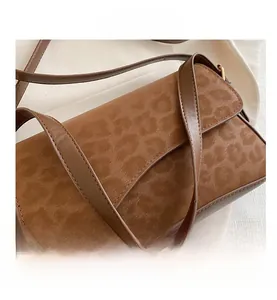 Détail du tissu en laine léopard et de la sangle texturée sur un sac à bandoulière brun