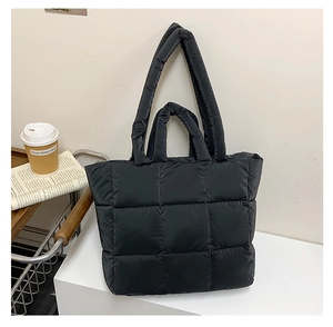 Close-up of black quilted puffer tote bag with durable padded straps and texture