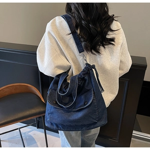 Détail du sac en jean avec poche à boucle métallique et accents de cordon latéral