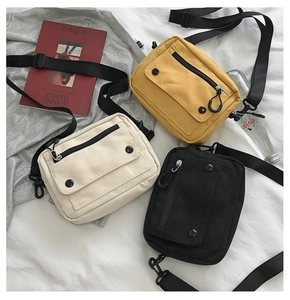 Flat lay of canvas crossbody bags in yellow, white, and black with adjustable straps