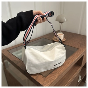 Dettaglio della borsa a tracolla bianca in nylon con cinturino a righe rosso bianco blu