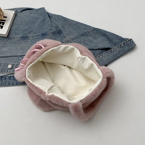 Pink plush tote bag with gold magnetic buckle and ribbon detail on denim background