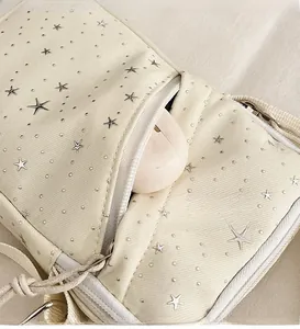 Detail of canvas crossbody bag with star embroidery showing the front zipper pocket utility