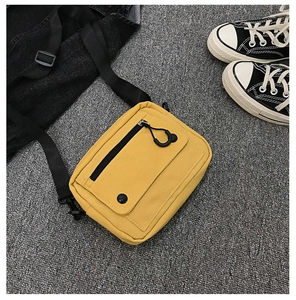 Detail of yellow canvas crossbody bag with adjustable strap and front zipper pocket