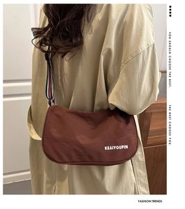Dettaglio della borsa a tracolla rosso-marrone con cinturino a righe tricolore