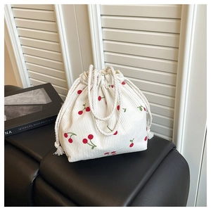 Detail der weißen Cordtasche mit Kordelzug und gestickten roten Kirschmustern