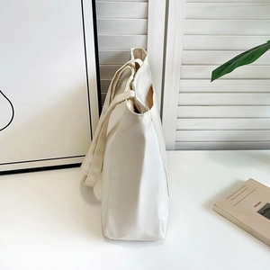 Side view of cream-colored nylon tote bag showing large capacity and sturdy handles