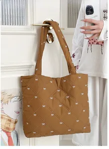 Detailed shot of brown quilted tote bag with white bows hanging on a white door handle
