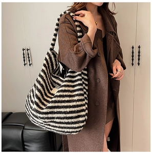 Detail of black and white striped plush knit shoulder bag paired with brown wool coat
