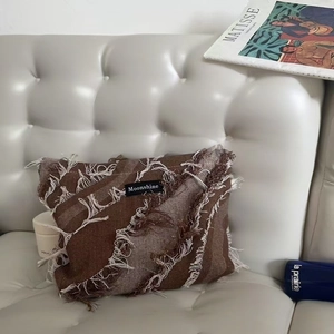 Denim fringe wash bag with Moonshine label on a white leather sofa background