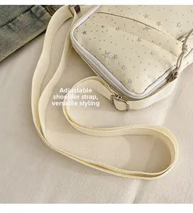 Detail view of adjustable canvas strap and silver star studs on cream shoulder bag