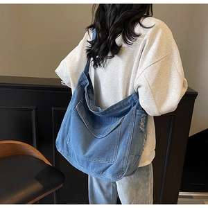 Détail du grand sac cabas en jean avec finitions usées et poches plaquées fonctionnelles