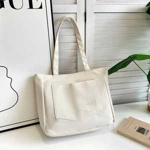 Detail of the white nylon tote bag showing front pocket with embossed FASHION lettering
