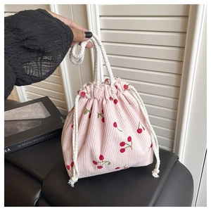 Detail der Textur der rosa Cord-Handtasche mit Kirschprint und dickem Baumwollkordelgriff