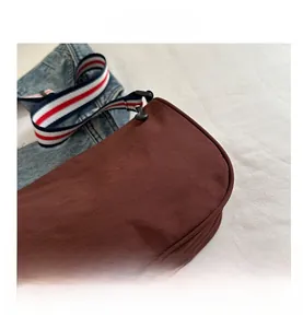 Dettaglio della borsa a tracolla marrone rossastro con la sua ampia tracolla a righe tricolore