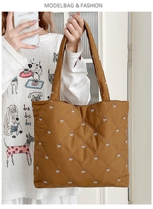 Detail view of brown quilted tote bag with white bow embroidery and diamond stitching
