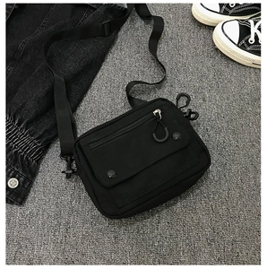 Detail of black canvas crossbody bag featuring front flap pocket and adjustable strap