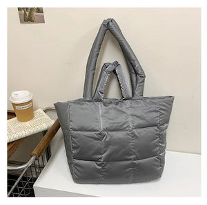 Detail of silver puffer tote bag featuring quilted texture and dual handles for shoulder use