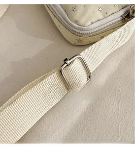 Detail of adjustable woven shoulder strap with silver square metal buckle on cream bag