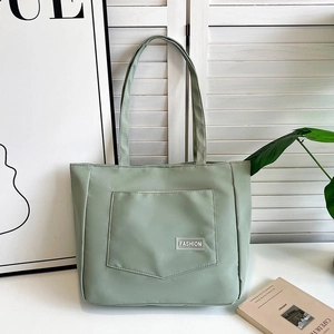 Close-up of light green nylon tote bag with a fashion label on the front pocket