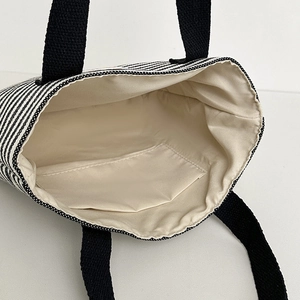 Chic black and white striped canvas tote bag with spacious interior and black strap handles