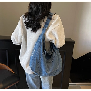 Détail de la boucle argentée ajustable sur le grand sac à bandoulière en denim bleu femme