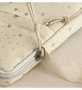 Close-up of beige canvas bag with silver star patterns and smooth metal zipper details