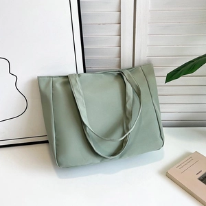 Detail of mint green nylon tote bag featuring wide straps and minimalist design