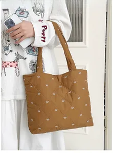 Close-up of brown quilted tote bag featuring elegant diamond texture and white bow patterns