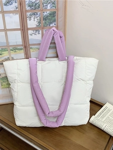 Quilted white puffer tote bag with purple padded handles and minimalist square stitching