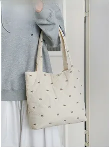 Close-up of beige diamond quilted tote bag with brown bow patterns and shoulder strap