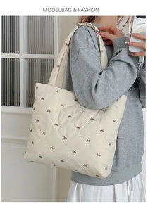 Detail view of cream quilted tote bag featuring delicate brown bow embroidery patterns