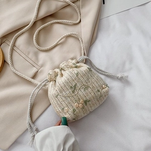 Détail du sac seau en paille tissée avec broderie florale et cordon de serrage en coton