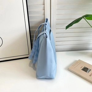 Detailed side view of light blue nylon tote bag showing spacious design and texture