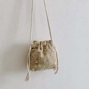 Détail du mini sac seau en paille avec broderie florale rose et bandoulière en coton