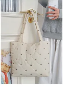 Detail of cream quilted tote bag with brown bow patterns and wide shoulder straps