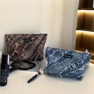 Detail of blue denim and brown tassel fringe makeup bags with Moonshine brand label
