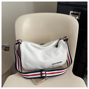 Dettaglio della borsa a mezzaluna in tela bianca con tracolla tricolore alla moda su sedia