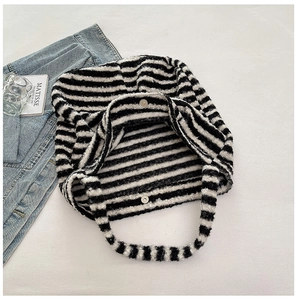 Close-up detail of plush black and white striped tote bag showing strong magnetic metal buckle