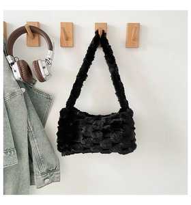 Detail of black faux fur shoulder bag with textured plush surface on a wooden wall hook