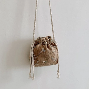 Détail du sac seau en paille tissé à la main avec broderie florale et cordon de serrage