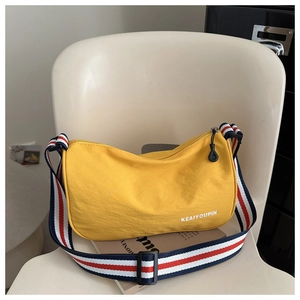 Dettaglio borsa a tracolla in tela gialla con ampia tracolla a righe e zip in metallo