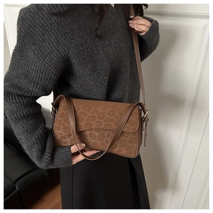 Détail d'un sac à bandoulière marron à imprimé léopard avec texture daim et lanière