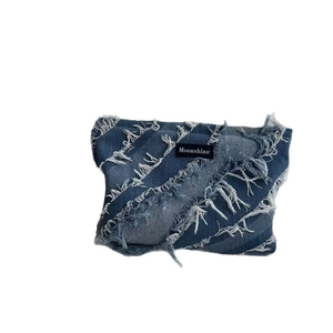 Blue denim patchwork toiletry bag with frayed edges and Moonshine label on white background