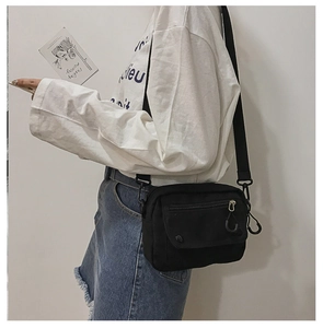 Side view of black canvas crossbody bag with adjustable strap shown on a model