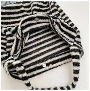 Detail of the black and white striped plush tote bag with a silver magnetic snap closure