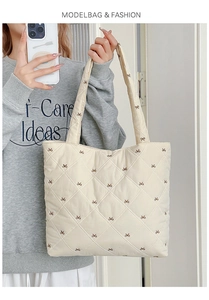 Detail of cream quilted tote bag featuring brown bow embroidery and diamond stitching